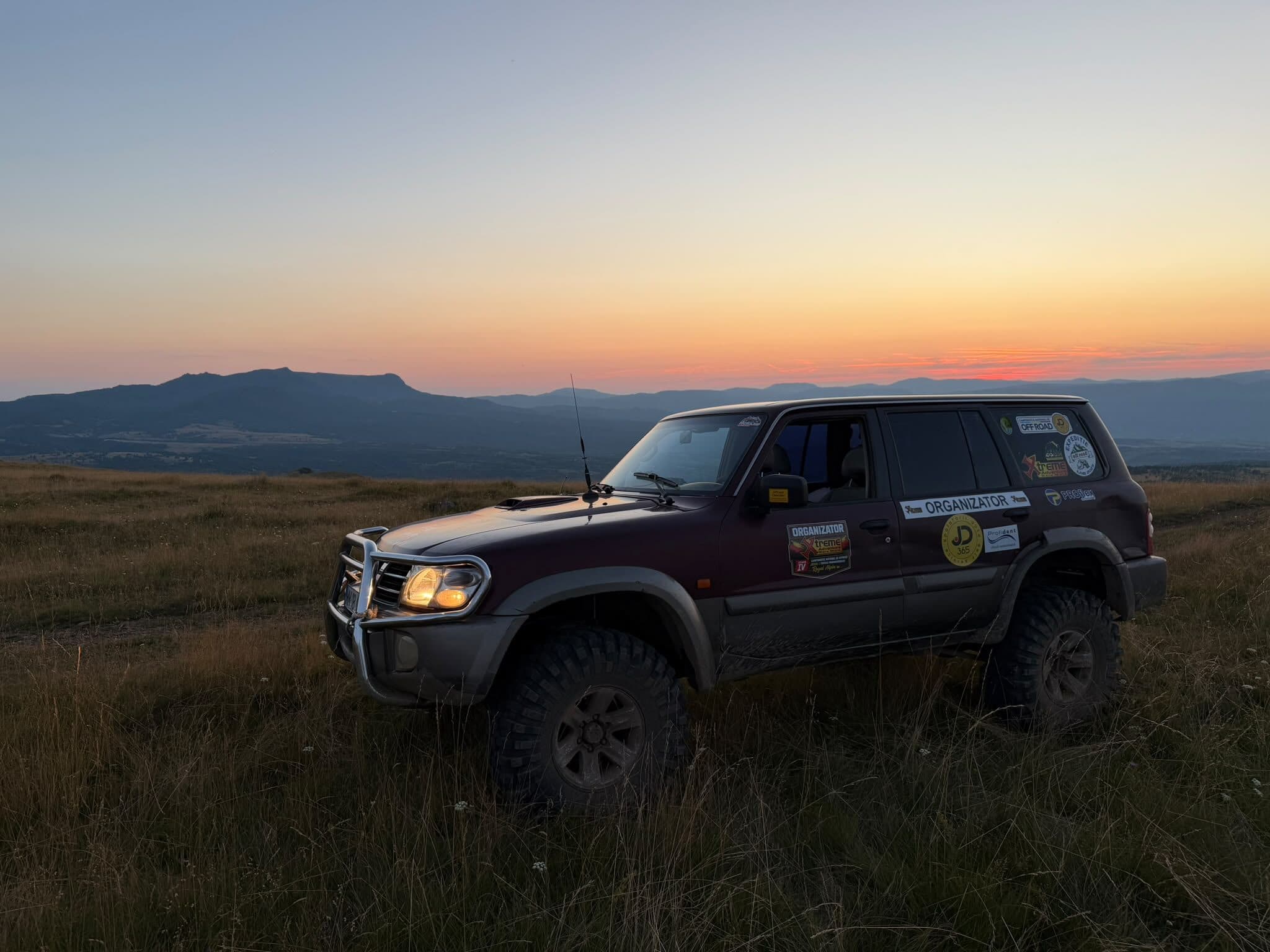 Nissan Patrol pe creastă la asfințit, cu munții în fundal
